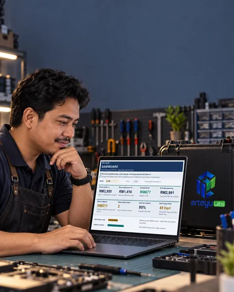 Pemilik kedai baiki di meja kerja tersusun, laptop terbuka, alat kabur di belakang